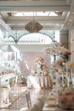 A brightly lit event space with a high ceiling, chandelier, and decorative elements.